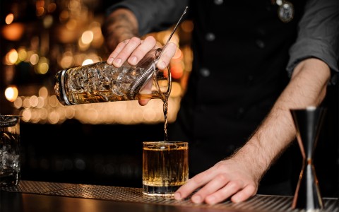 a person pouring a drink into a glass