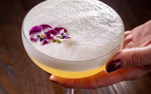 a hand holding a drink with flowers on it