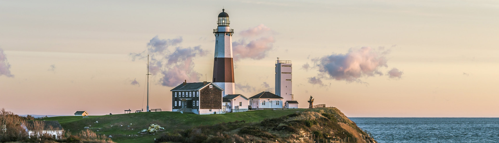 A red and white lighthouse located next to the shoreline at sunset,