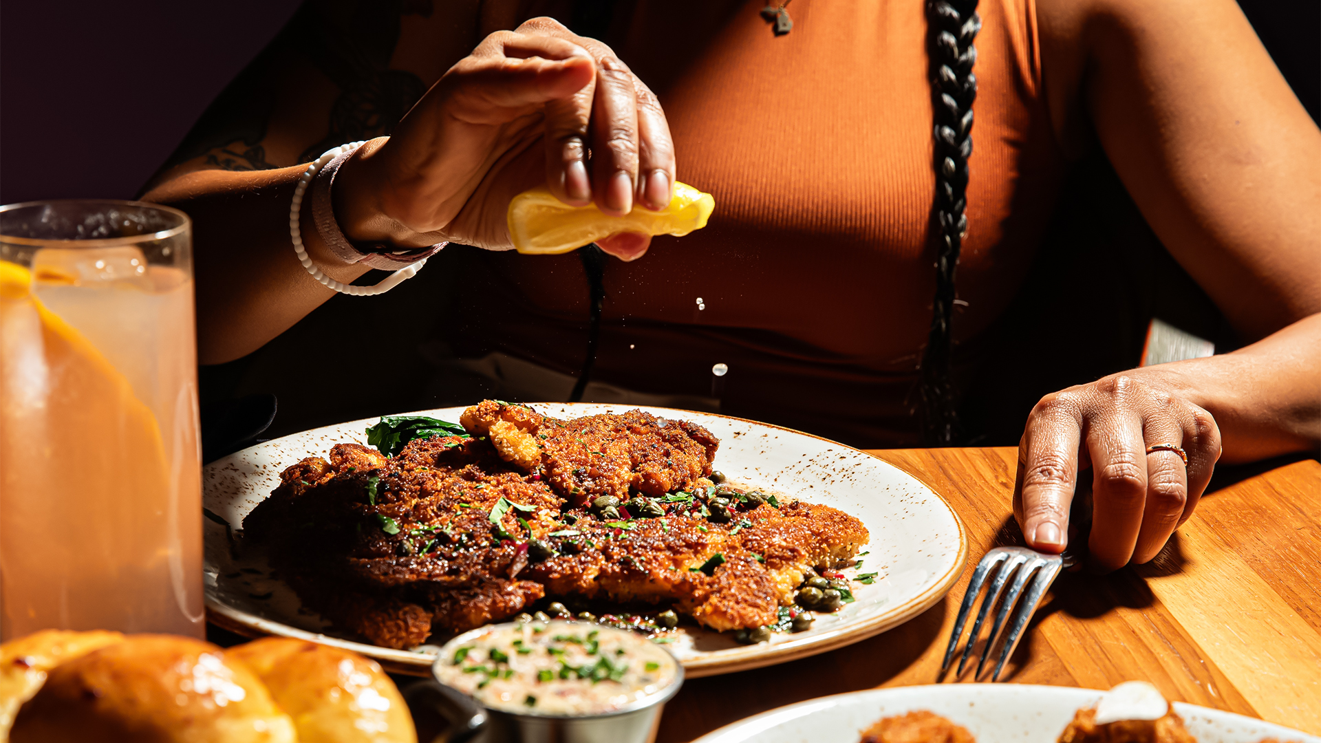 a person squeezing lemon on a plate of food