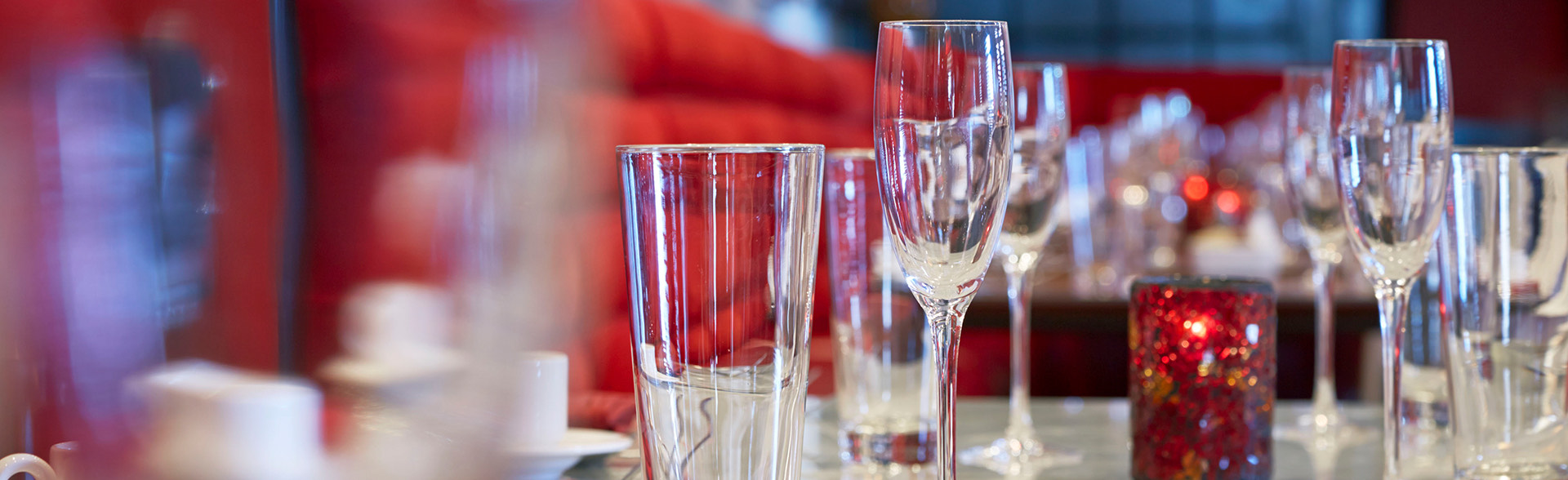 Drinking glasses and red candle on tabletop.