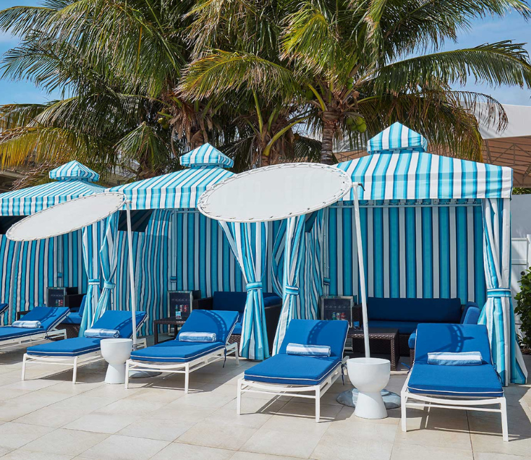 a group of lounge chairs under a palm tree