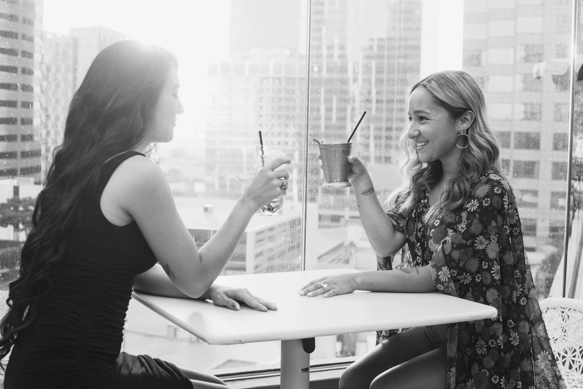 two women sitting at a table with drinks