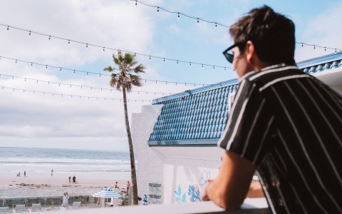 a man leaning on a railing overlooking a beach