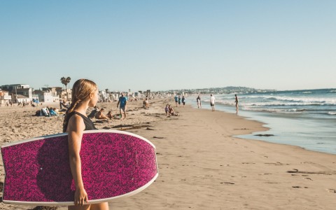 a woman carrying a surfboard on a beach
