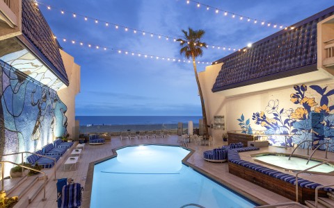 a pool and palm trees with lights from a string