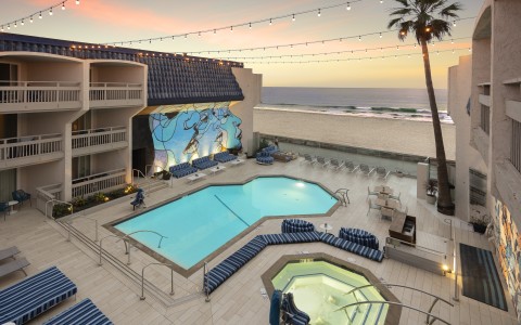 a swimming pool and a hot tub with a palm tree and a beach