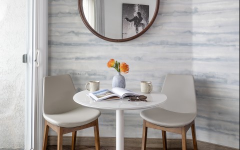 a round mirror above a table with chairs