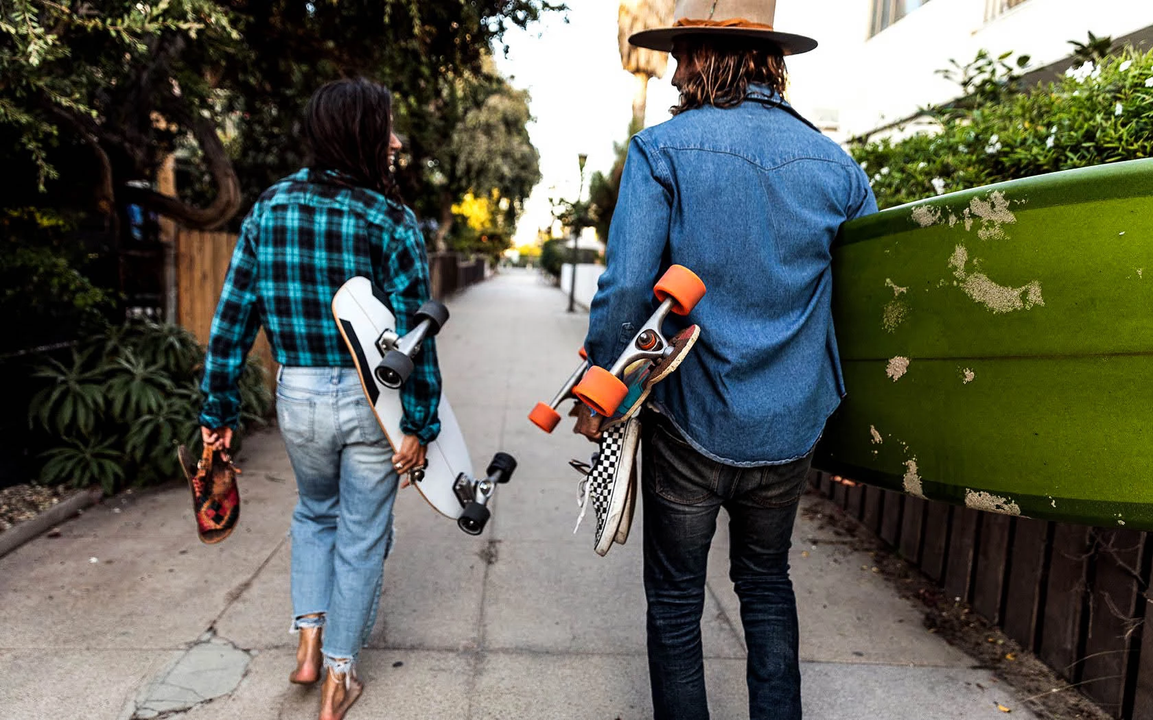 woman and man holding skateboards walking