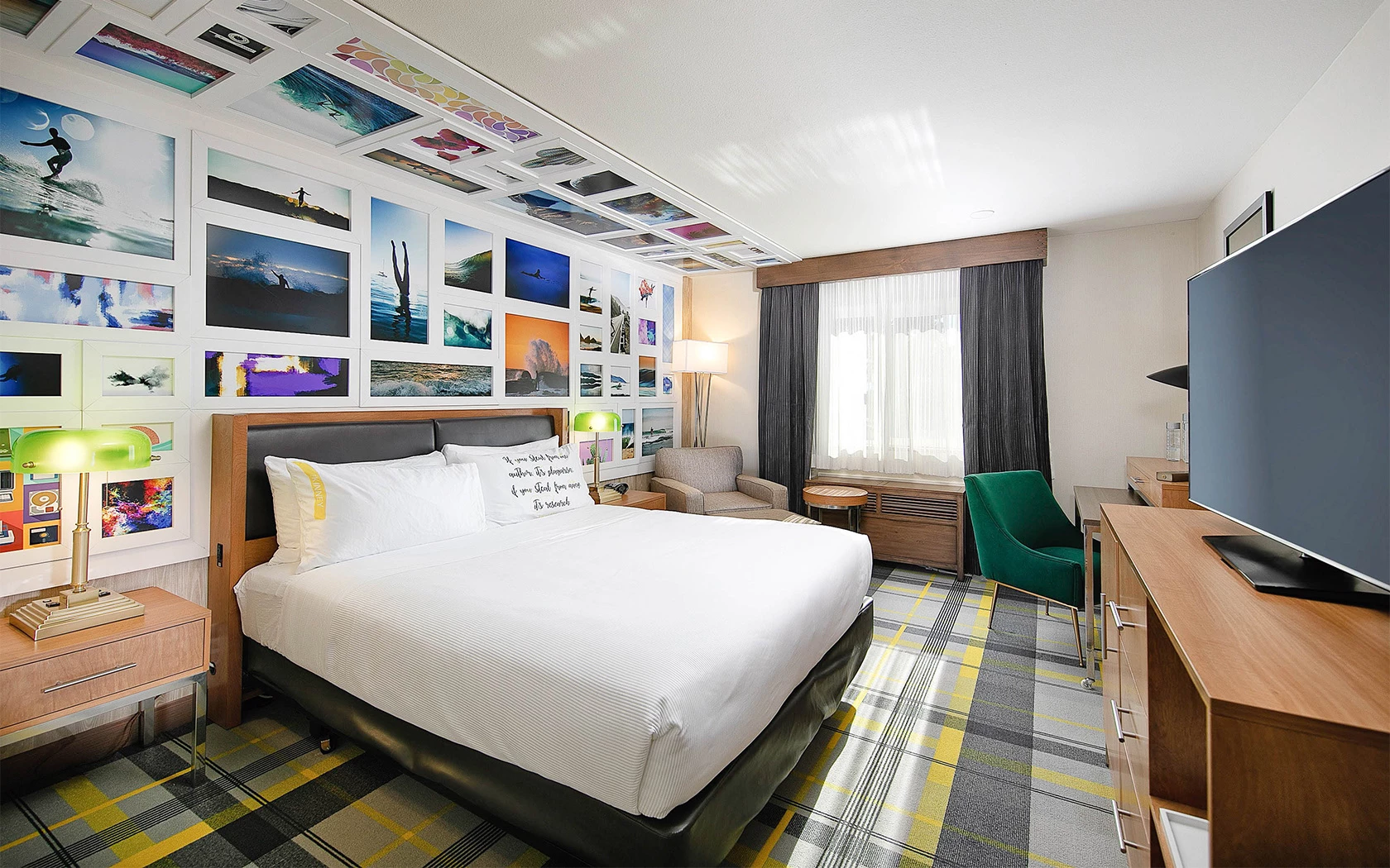 bed with white sheets, green desk chair, and tv across from bed