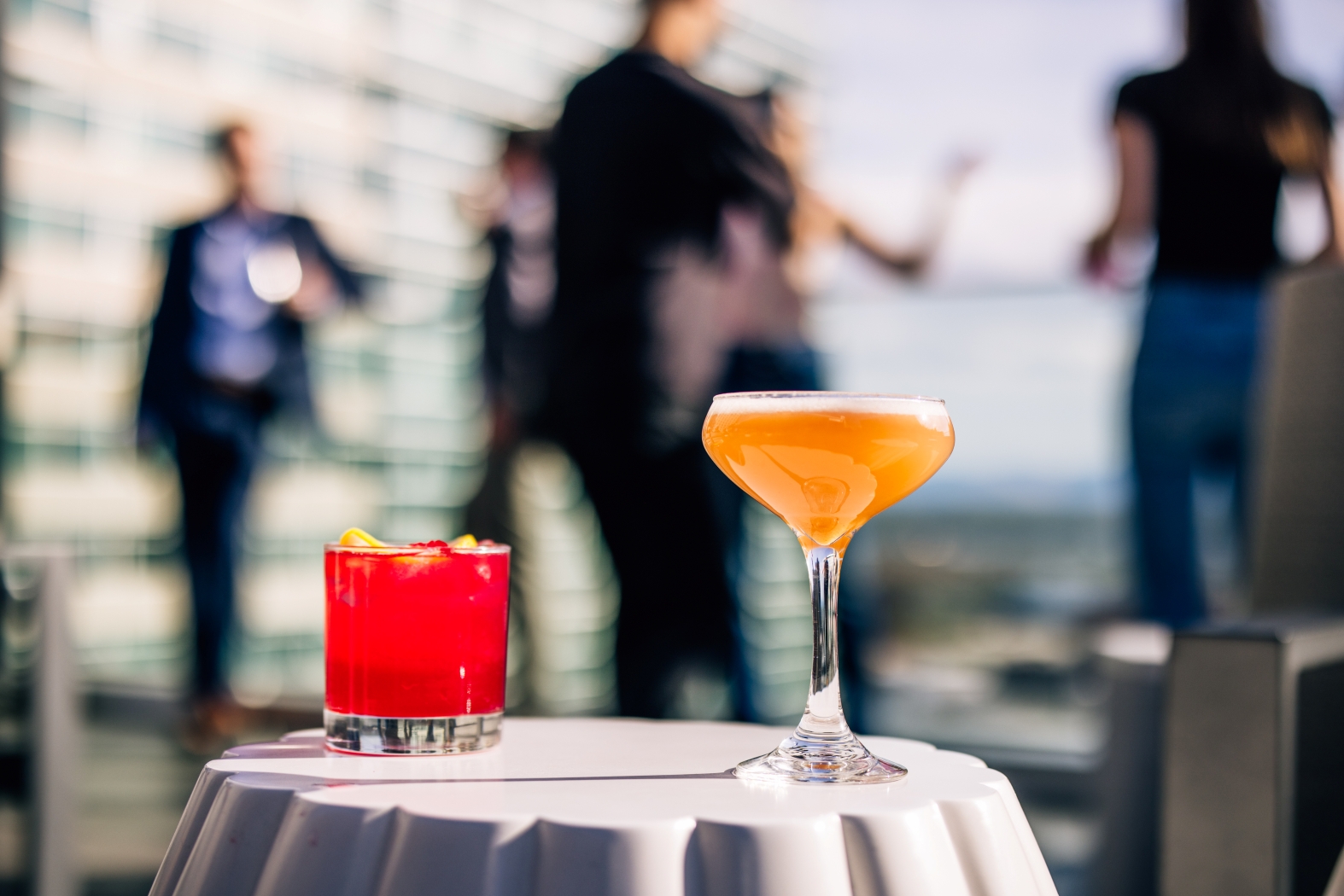 a glass of orange liquid and a red drink on a white table