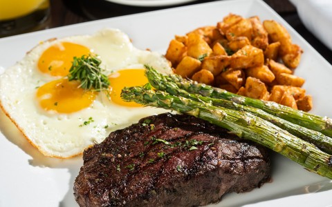 a plate of food with eggs asparagus and steak