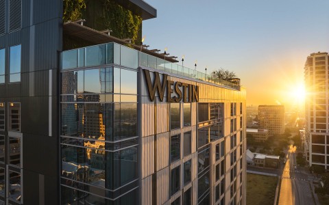a building with a glass wall and a city in the background