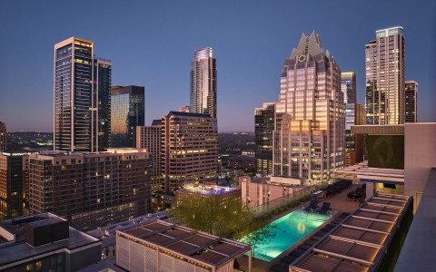 a rooftop view of a city with a pool and buildings