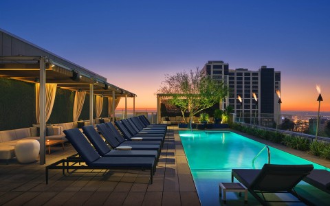 a pool on a rooftop with chairs and trees