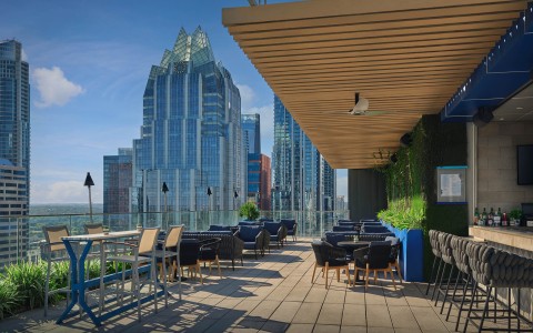 a rooftop patio with tables and chairs and a city skyline