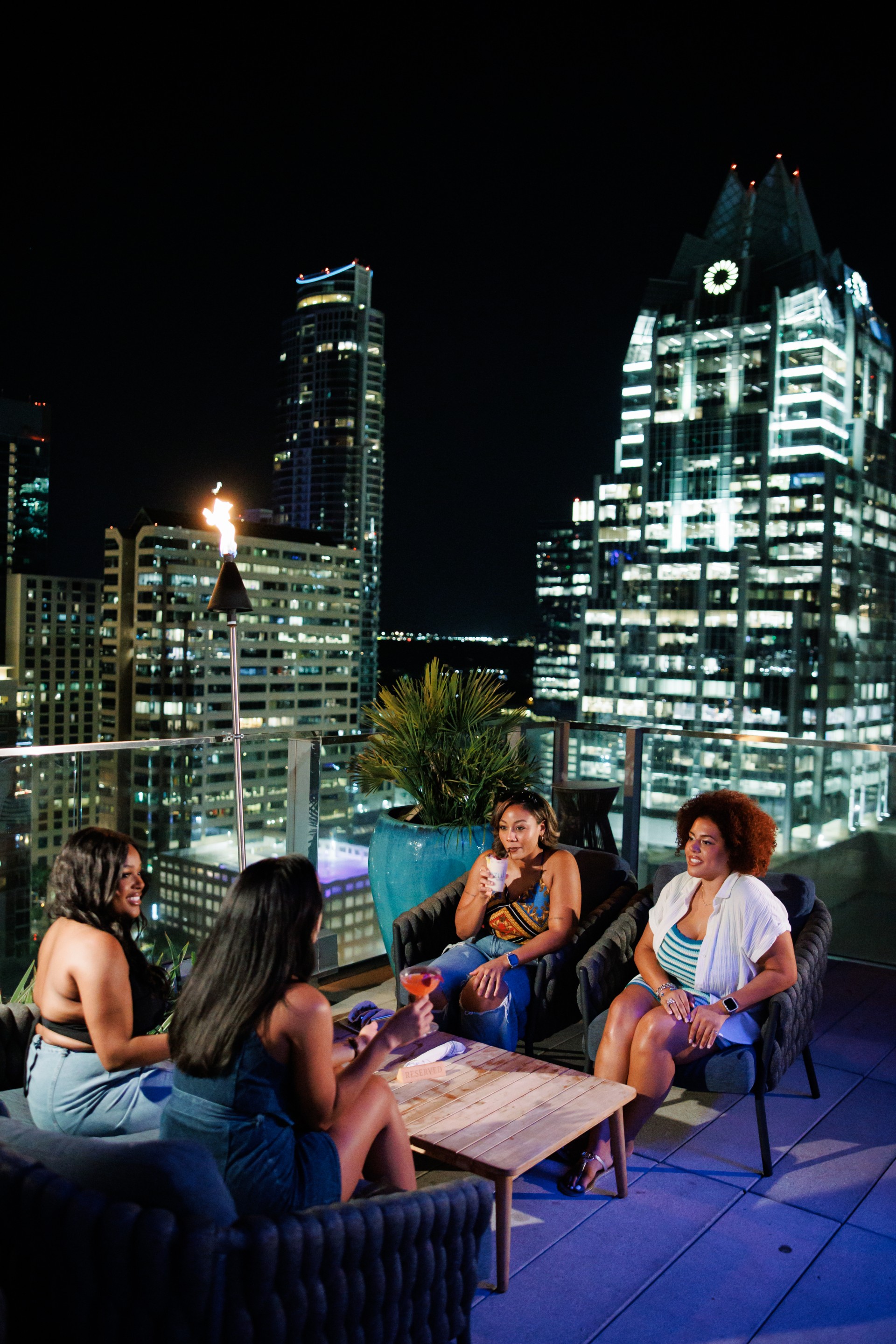 a group of women sitting on a patio with a fire in the background