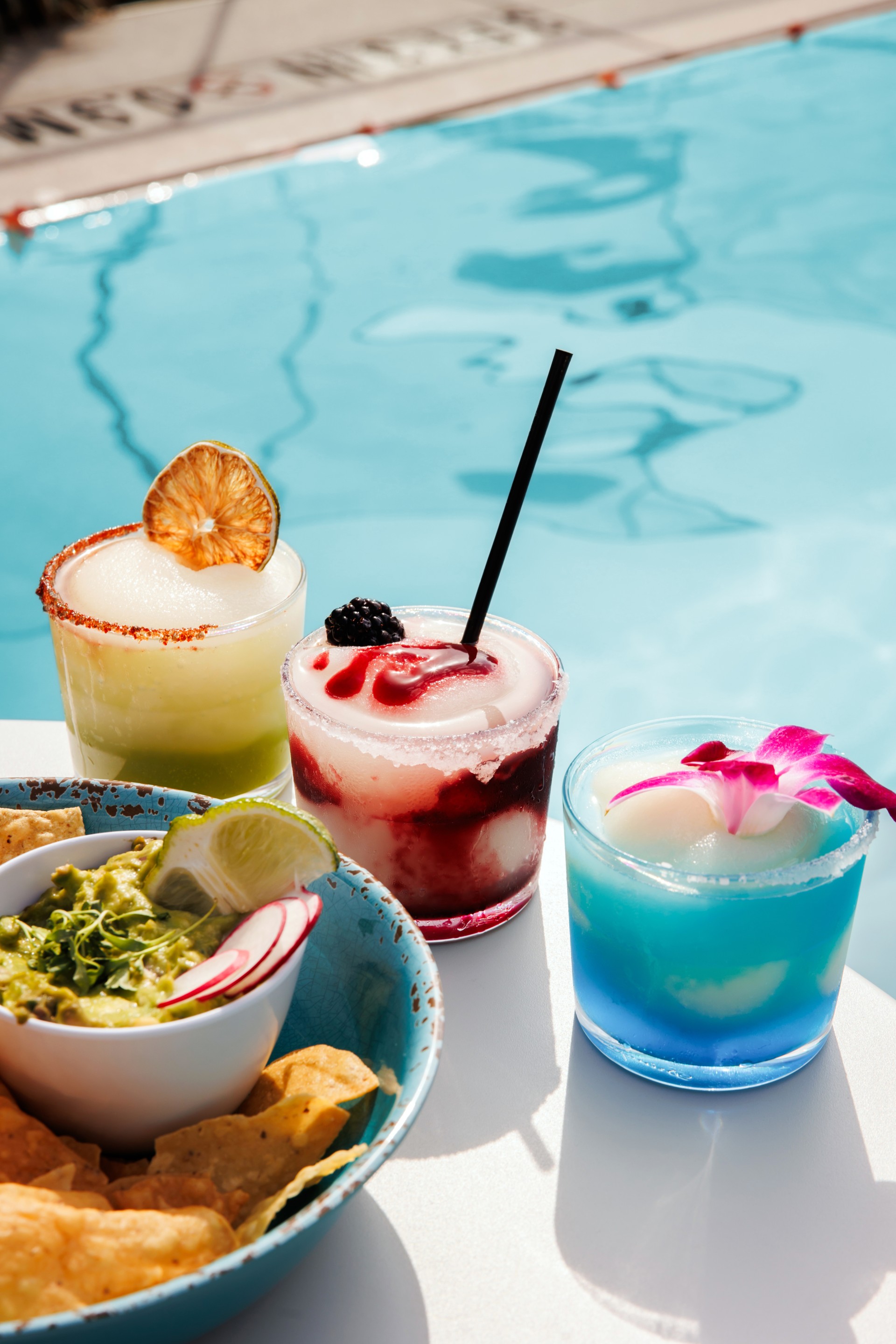 a group of drinks on a table next to a pool