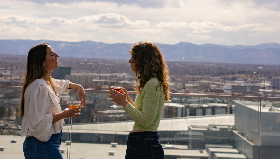 a woman holding drinks and talking to another woman