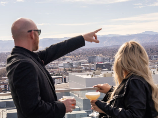 a man and woman holding drinks and pointing at each other