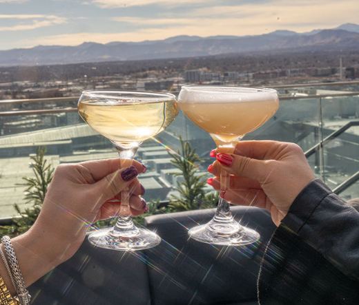 two hands holding glasses with drinks