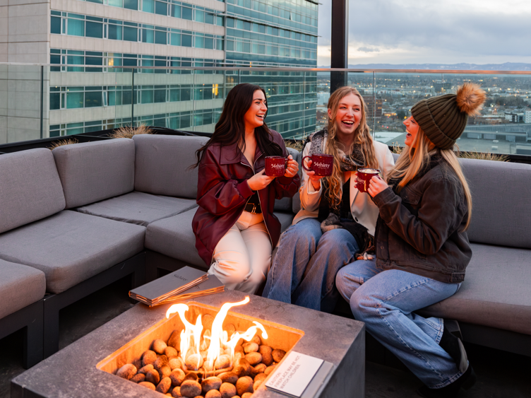 a group of women sitting on a couch with a fire pit