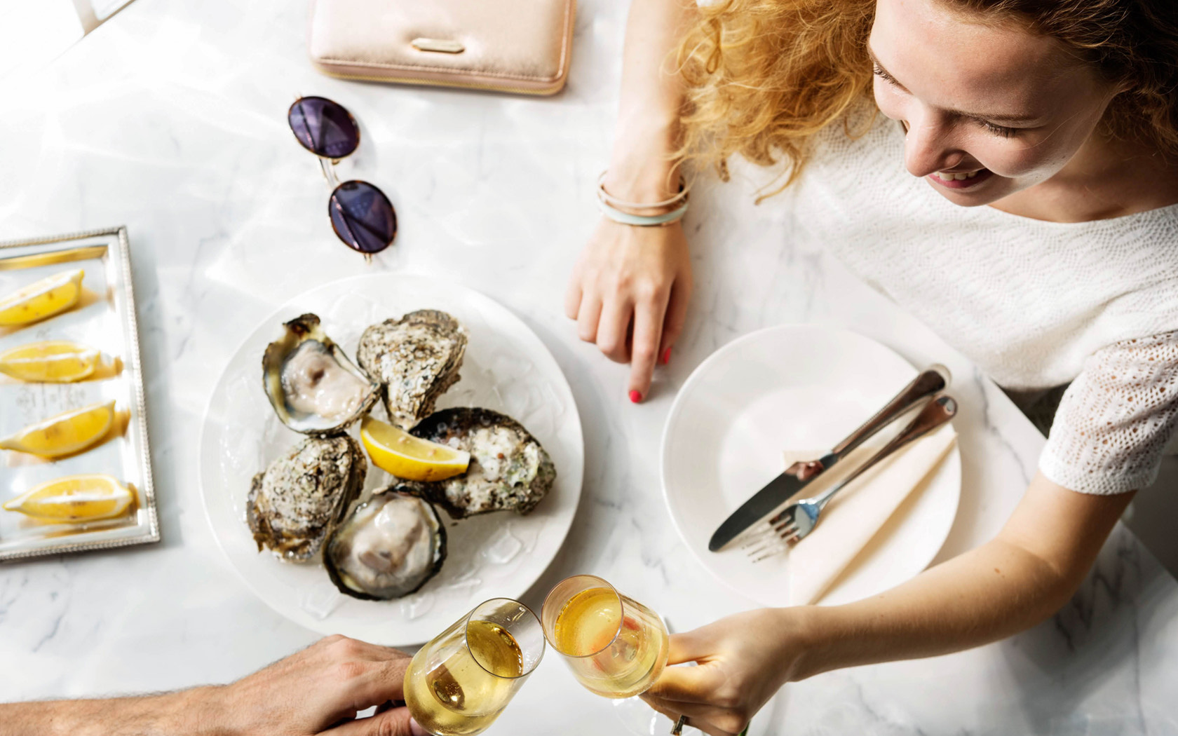 a woman sitting at a table with food and drinks