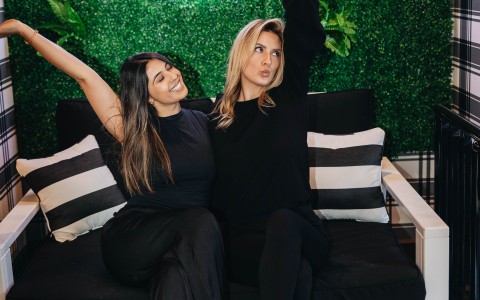 two women sitting on a couch with their arms up