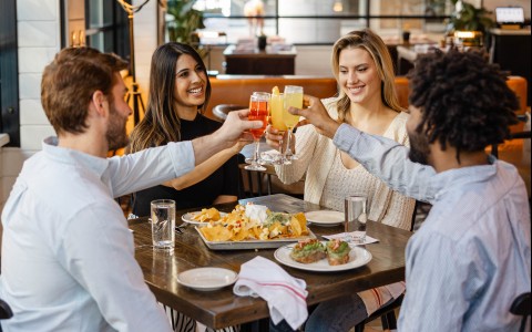 a group of people sitting at a table with food and drinks