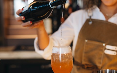 a woman pouring a drink into a glass