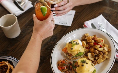 a person holding a drink and a plate of food