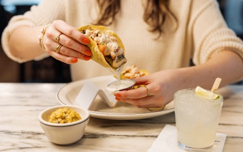 a person pouring sauce onto a taco