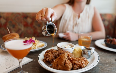 a person pouring sauce on a plate of food