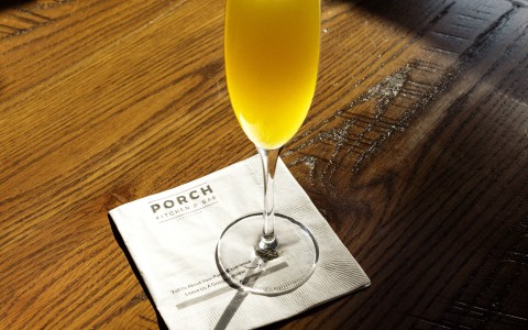 a glass of yellow liquid on a napkin on a wooden table