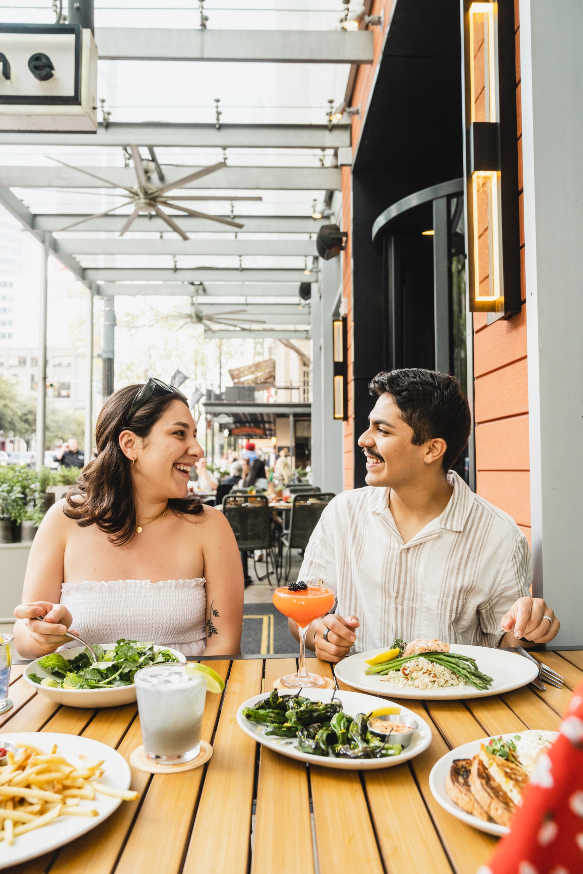 a man and woman sitting at a table with food