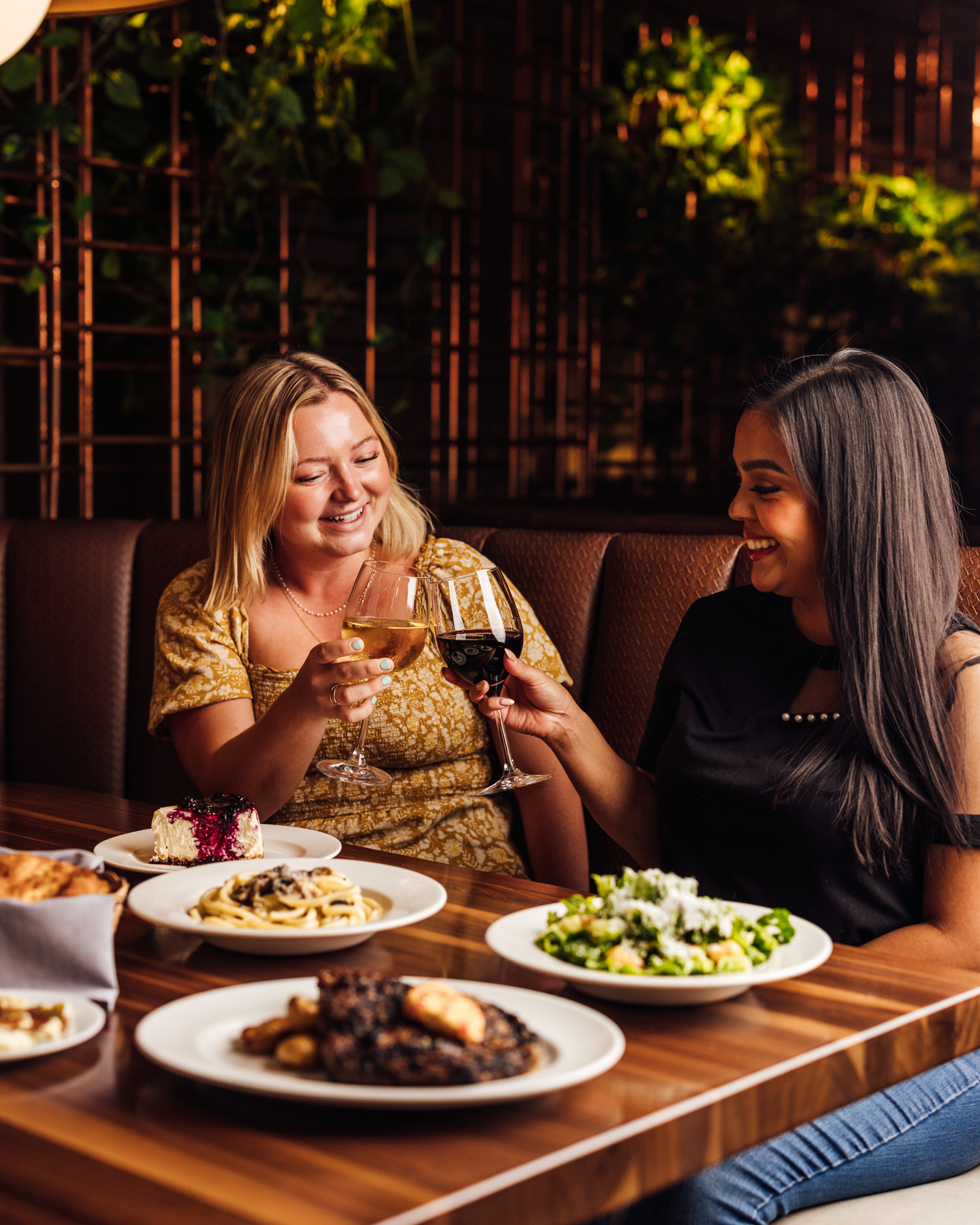 two women sitting at a table with food and drinks