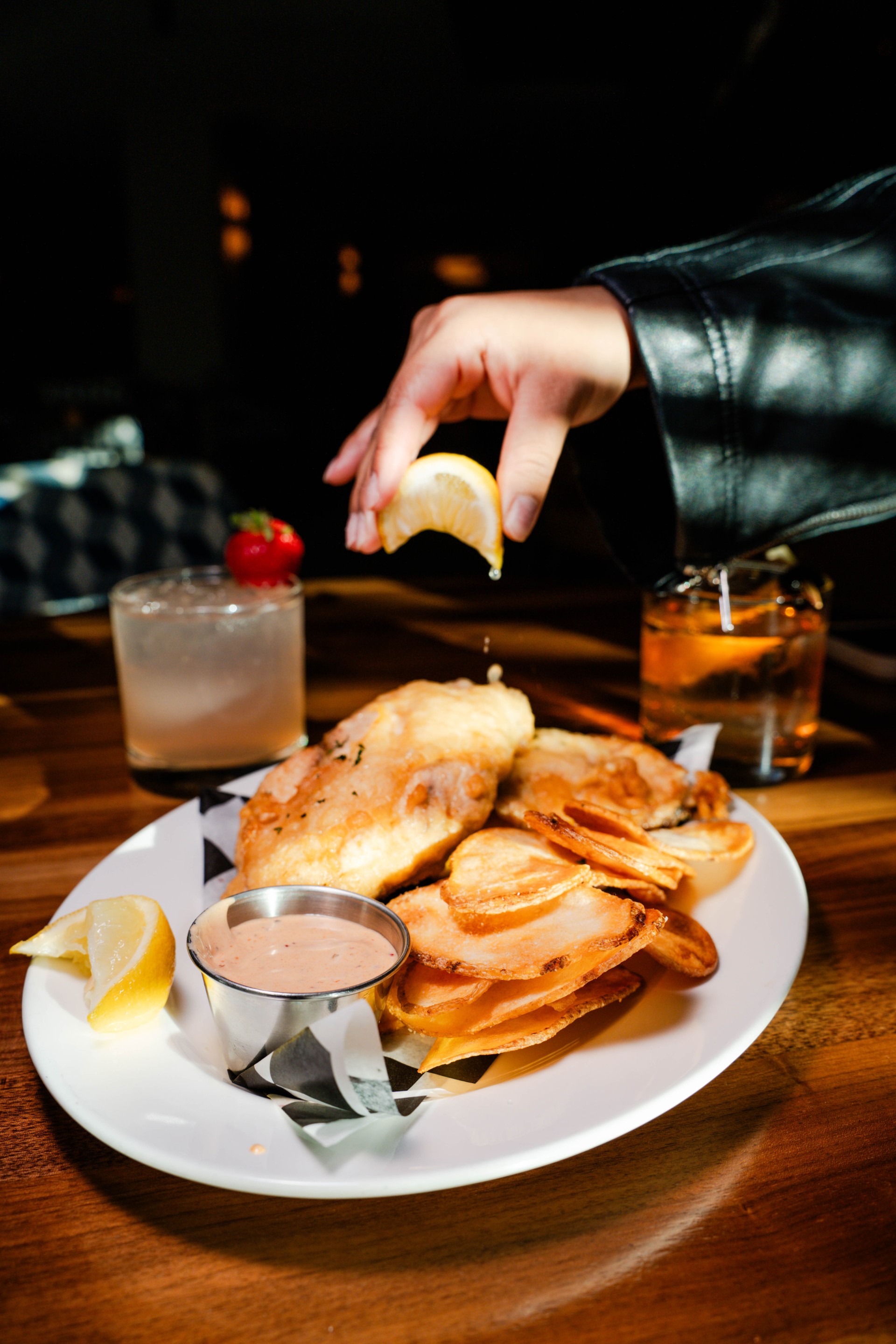 a hand putting lemon on a plate of food