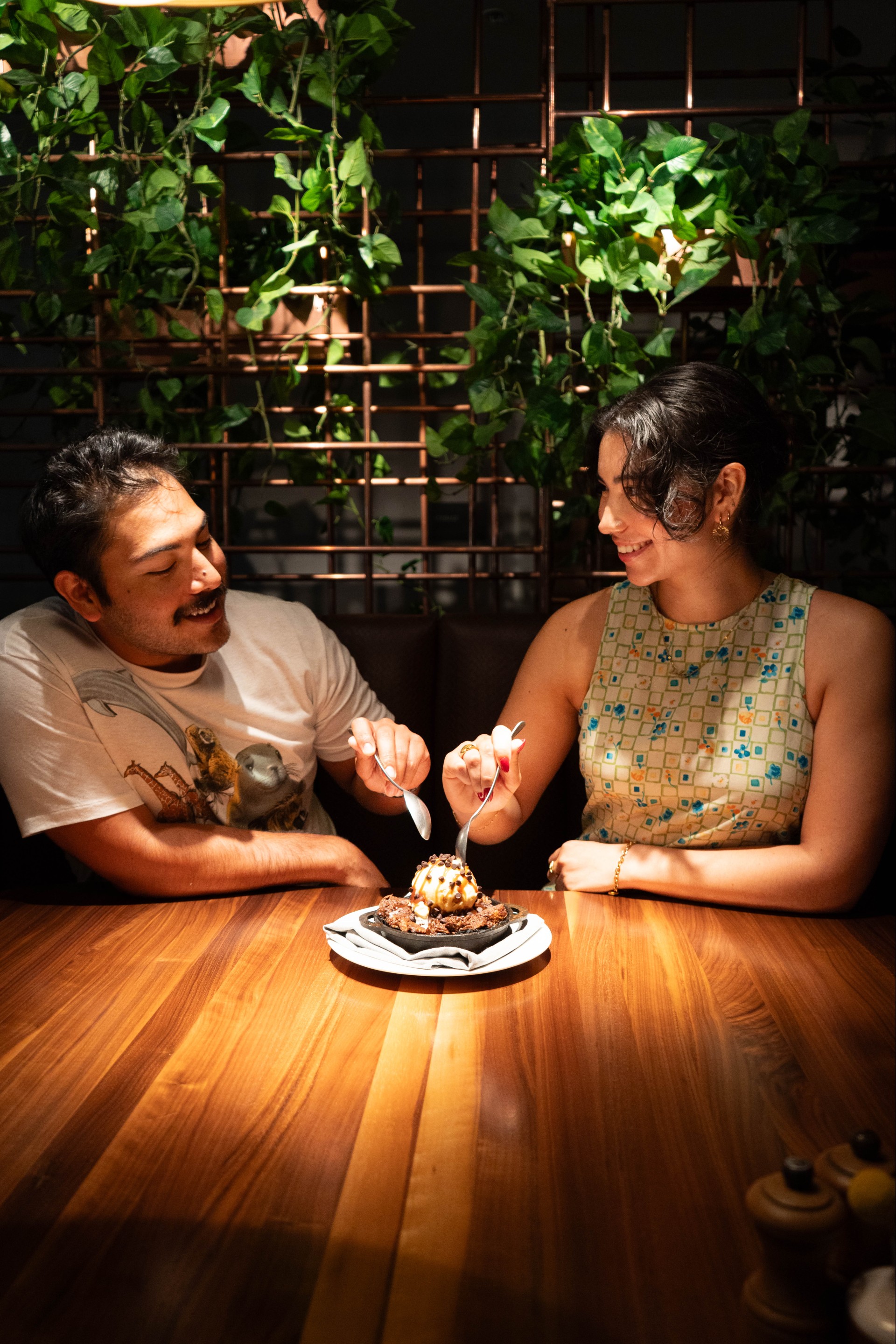 a man and woman sitting at a table eating a cake