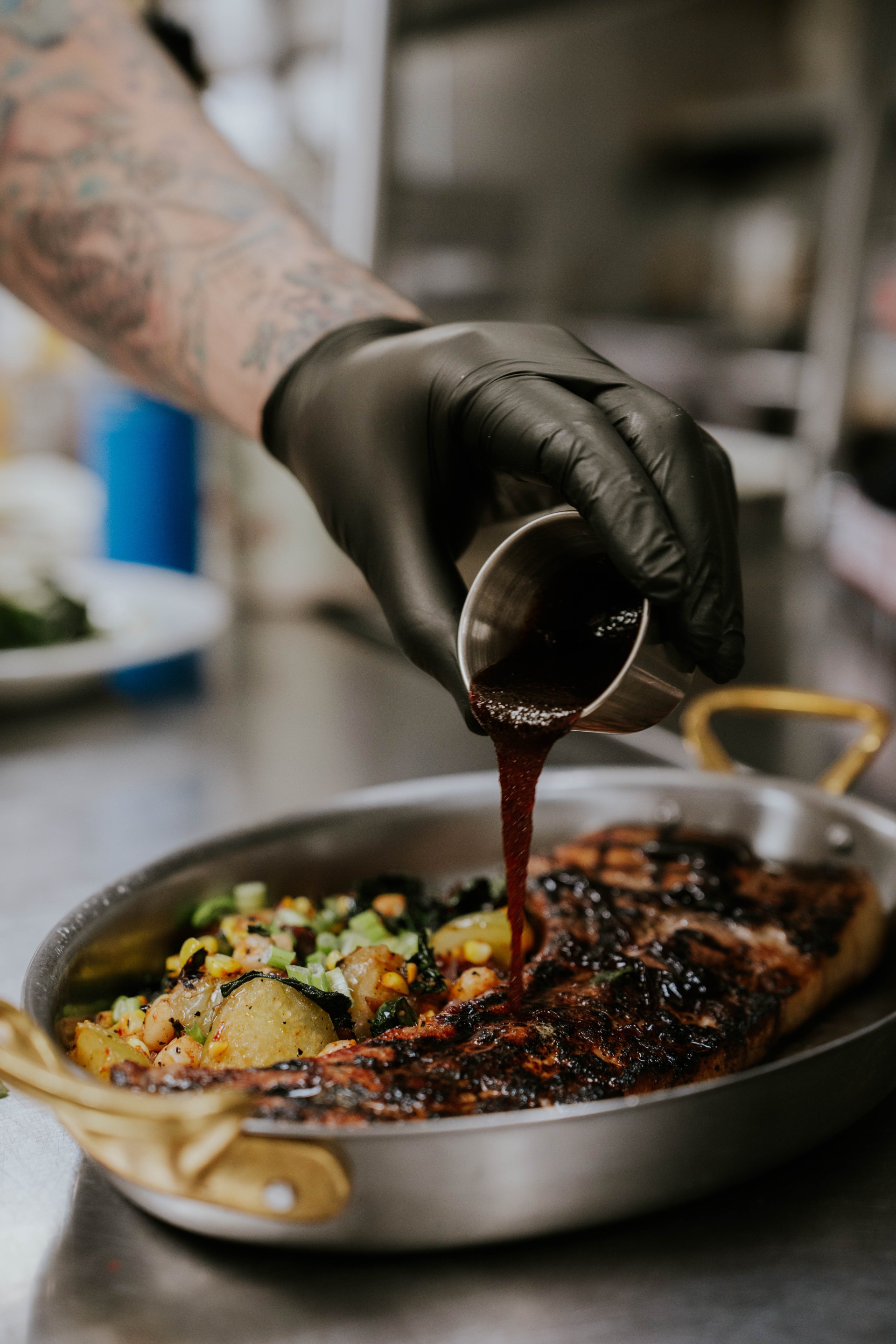 a person pouring sauce on a meat dish