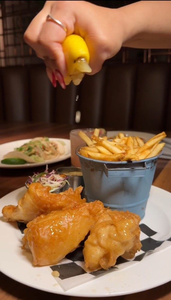 a hand dipping a potato into a bowl of fries