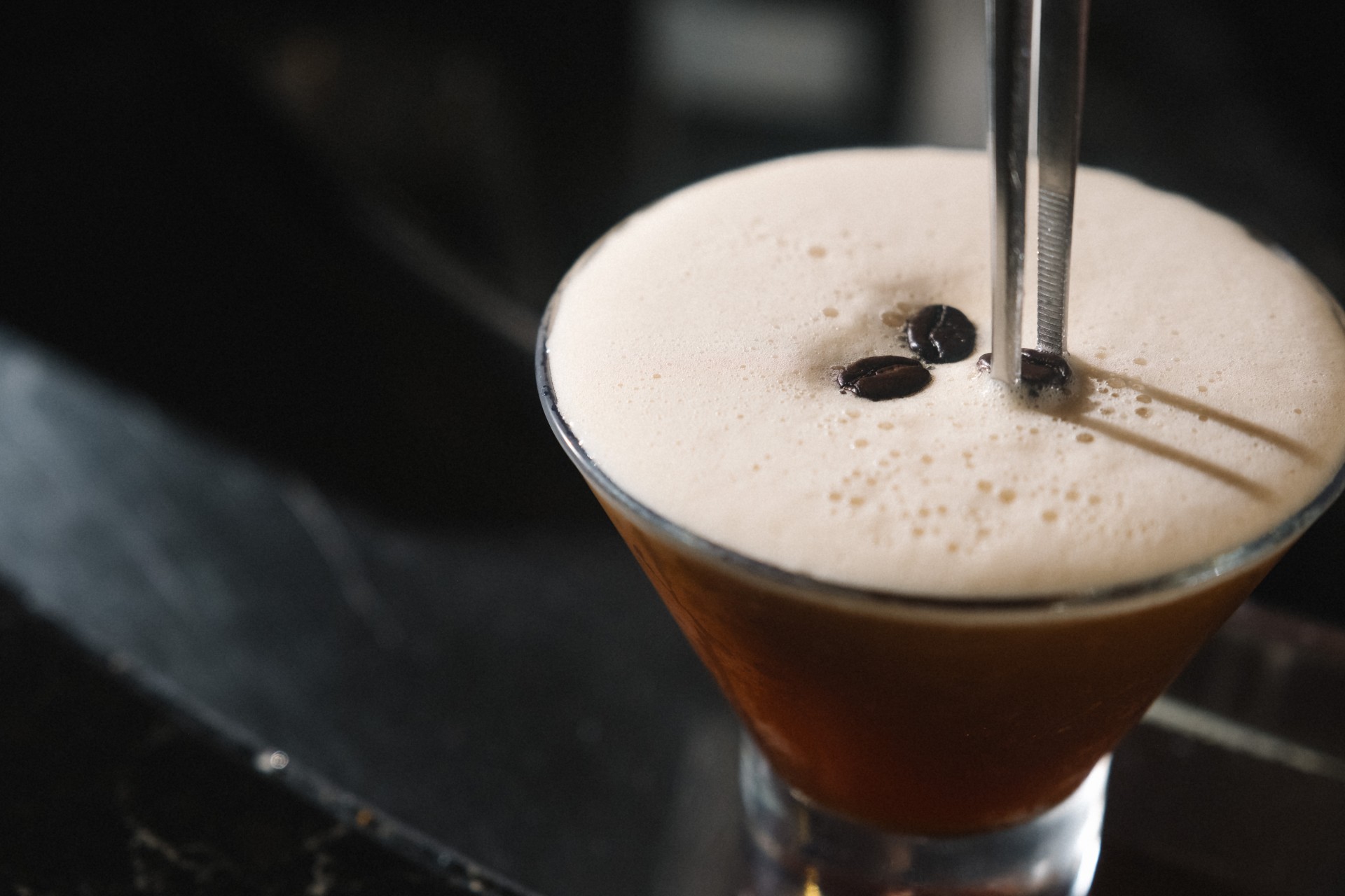 a glass with brown liquid and coffee beans