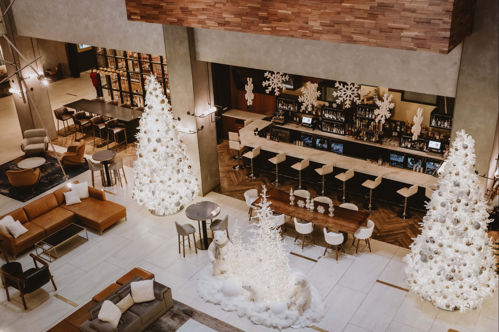 a room with white christmas trees and tables and chairs