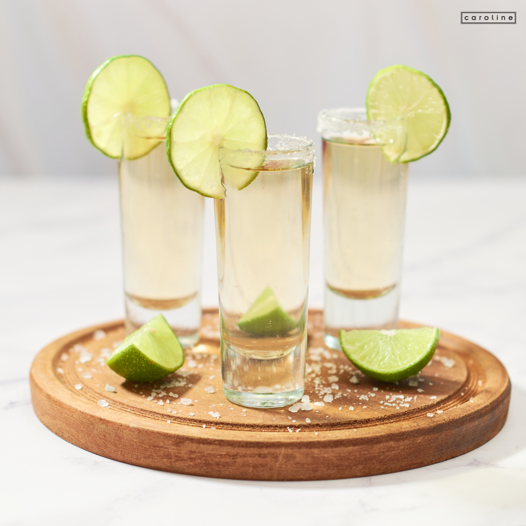a group of glasses with liquid and lime slices on a wooden board