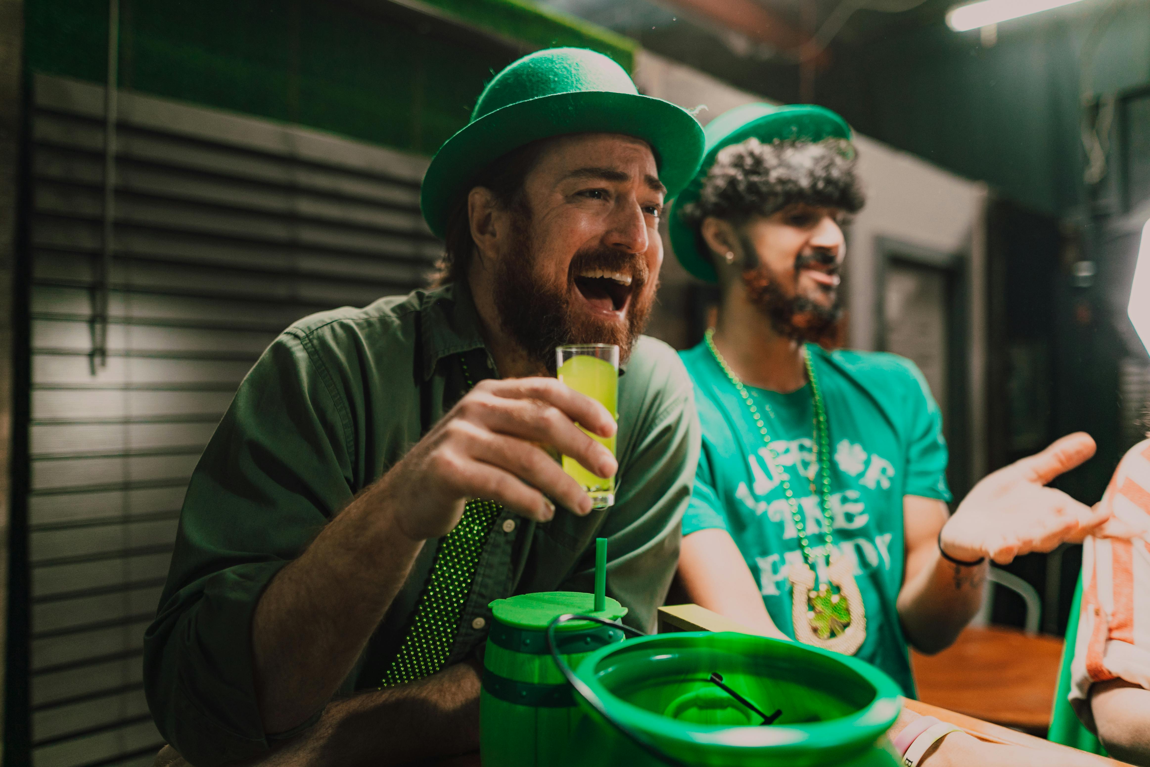 a group of men wearing green hats and holding a drink