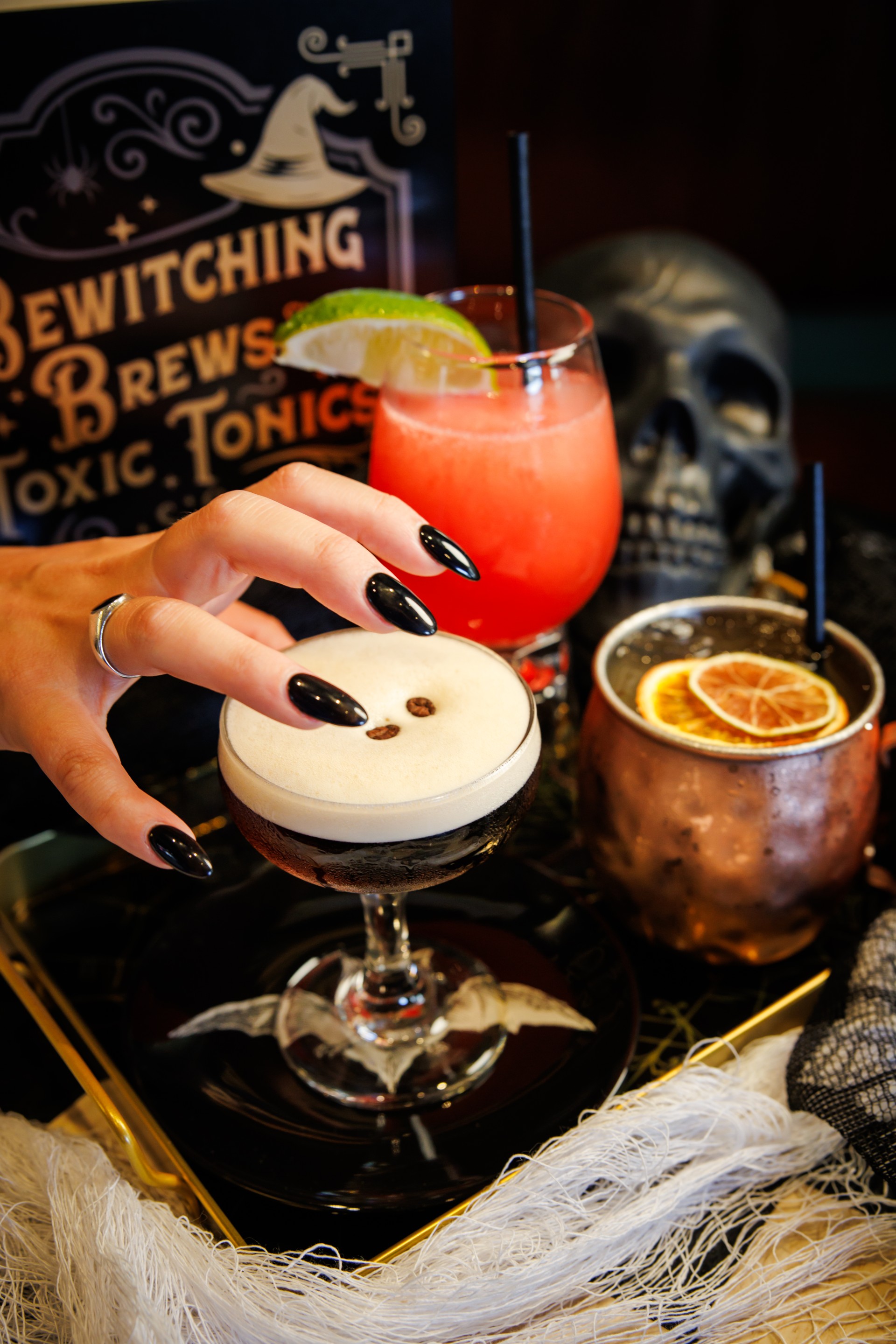 a hand with black nails over a drink