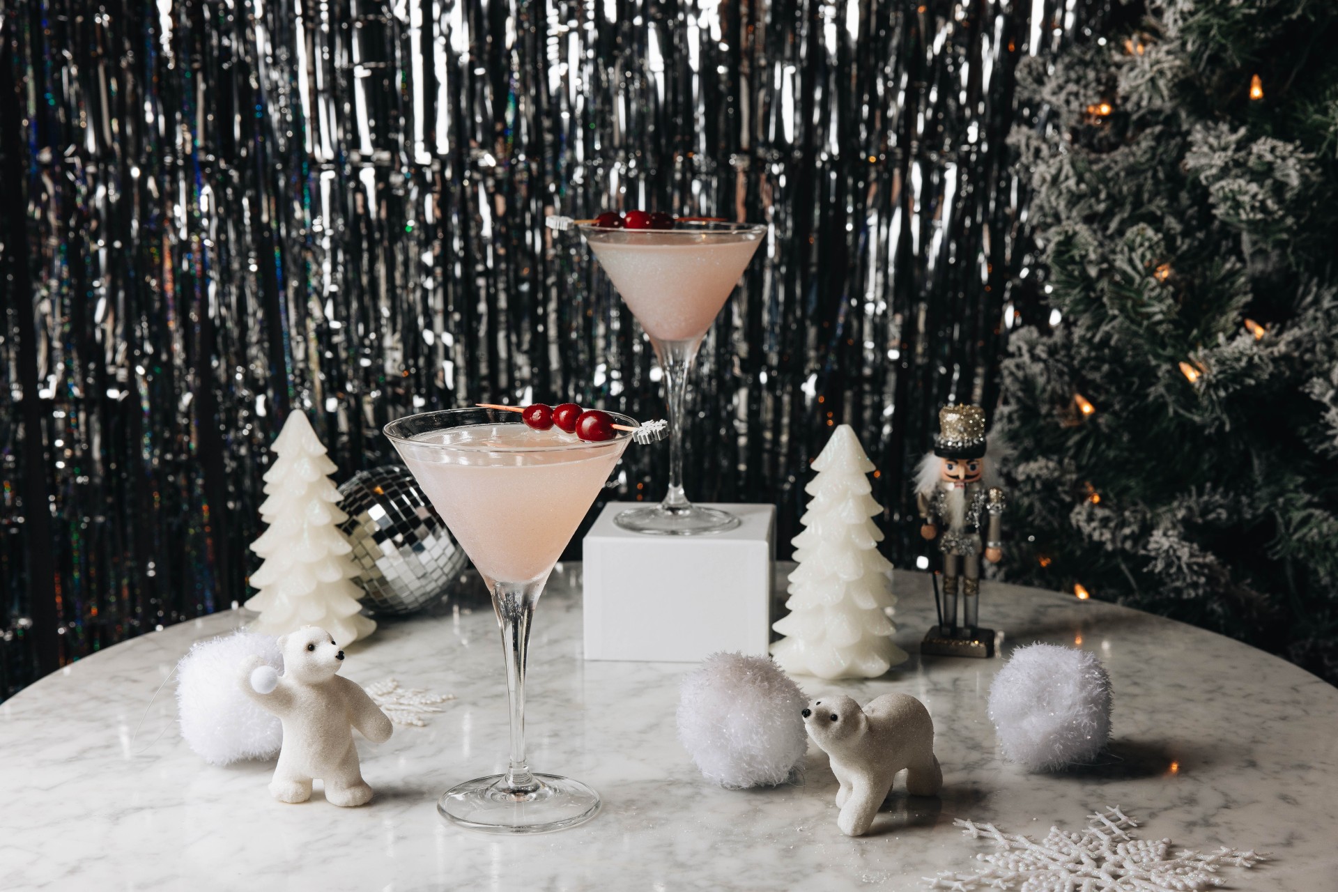 a pink drink with cherries in a martini glass
