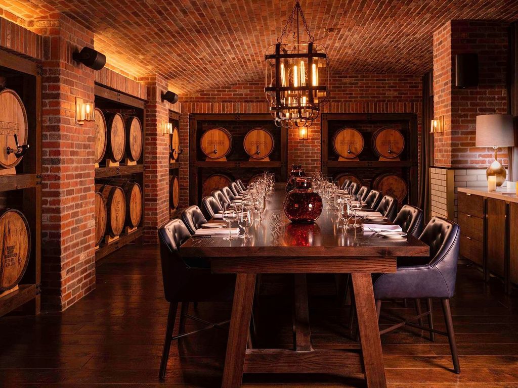 a long table with chairs and wine glasses in a room with brick walls