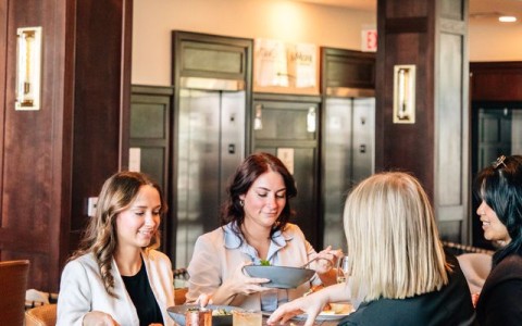 a group of women sitting at a table eating food main