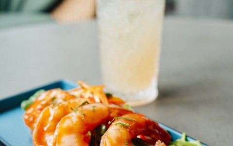 a plate of shrimp with sauce and a drink