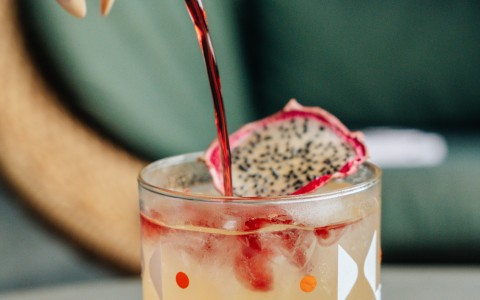 a person pouring a drink into a glass